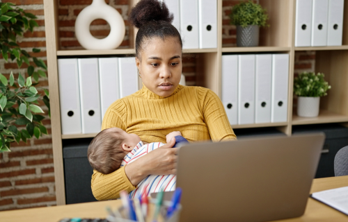 A woman breastfeeds while working at a computer