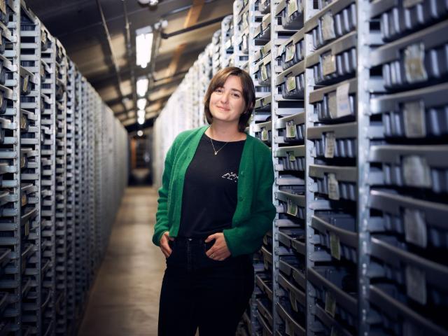 Jessie George stands between rows of archival drawers in the “primary range,” a catacomb-like area at the La Brea Tar Pits where fossil collections are stored.